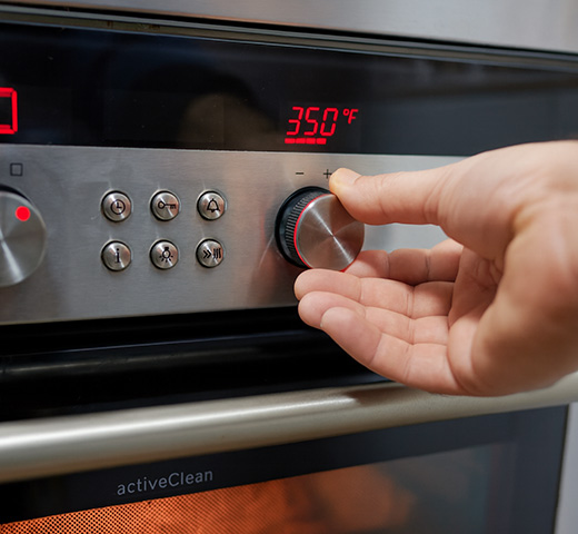 A person adjusting the temperature dial on an oven